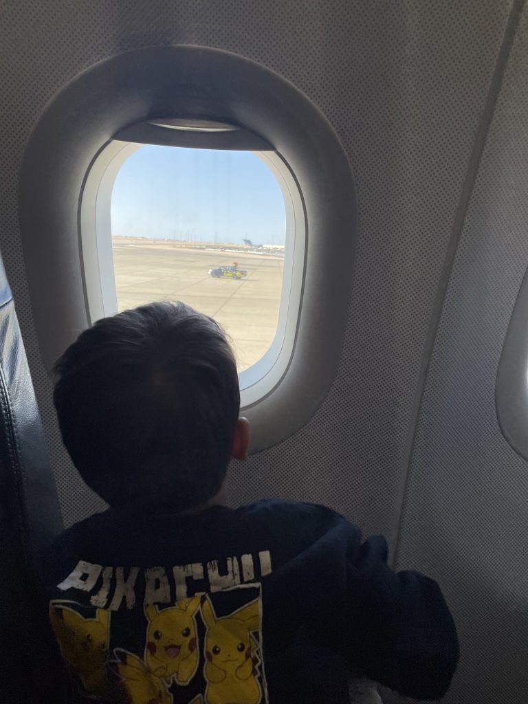 Kleinkind schaut aus dem Flugzeugfenster – Handgepäck Kleinkind Flug